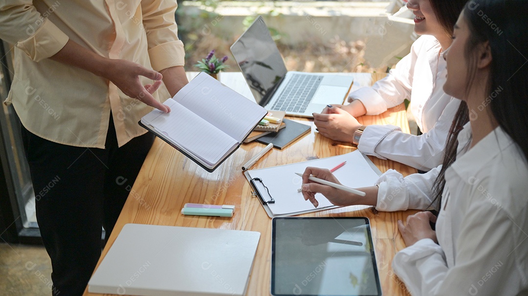 Foto recortada de A Um grupo de jovens profissionais está pesquisando e fornecendo informações para se preparar para projetos futuros. Com um laptop e notebook