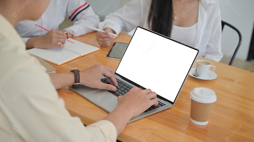 Foto recortada de Um grupo de jovens profissionais está procurando informações do laptop e tomando notas para propostas de gerenciamento para projetos futuros.