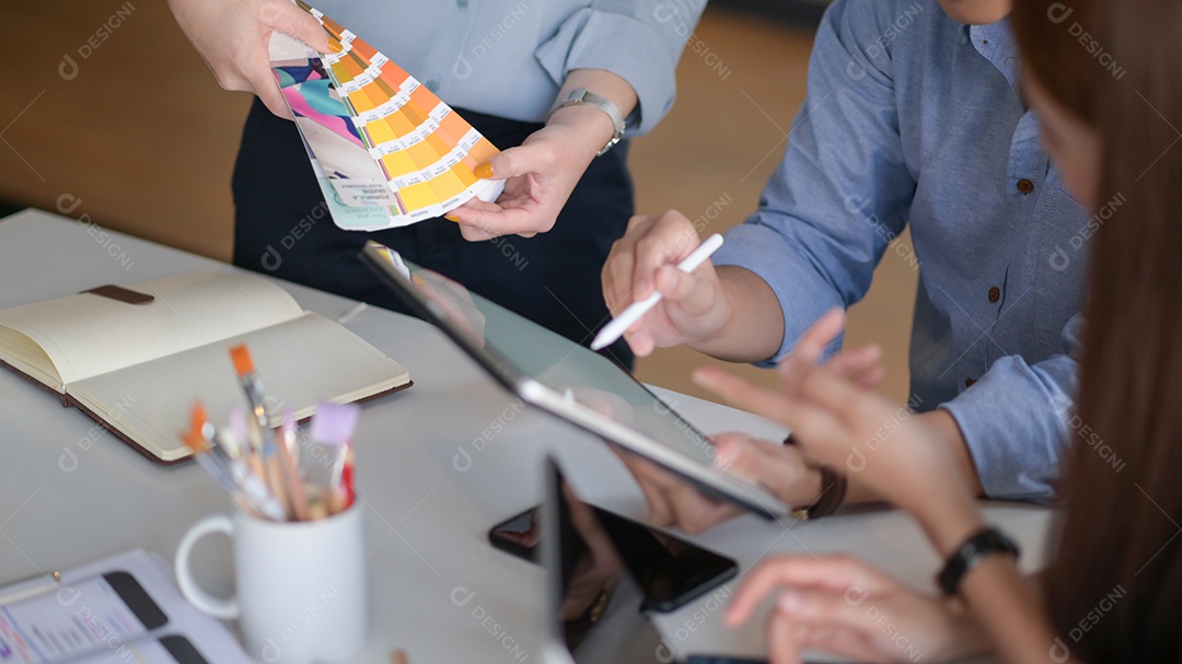 Shot de Uma equipe de designers profissionais usando tablet e dispositivos está debatendo ideias para criar projetos para clientes.