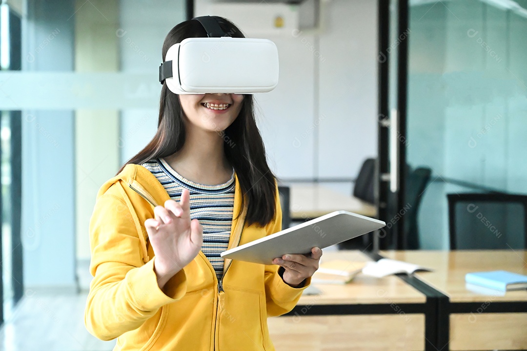 Foto recortada de uma jovem estudante usando óculos VR e usando um laptop.