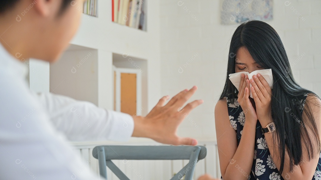 Foto recortada de uma jovem espirrando enquanto trabalhava com um parceiro masculino. Ele estava apavorado com o Covid-19.