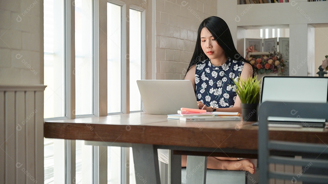 Foto recortada de jovem asiática está trabalhando em casa com seu laptop para proteger contra o vírus Corona ou Covid-19.