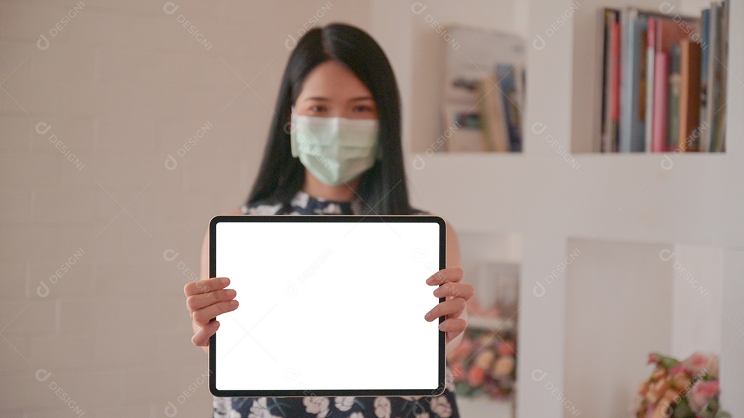 Mulher asiática usando uma máscara segurando um tablet voltado para a tela frontal para uma mensagem para proteger contra o vírus Corona ou Covid-19.