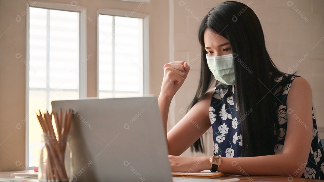 Garota usando uma máscara com gestos confiantes Ela trabalha em casa para se proteger contra o vírus Covid-19.