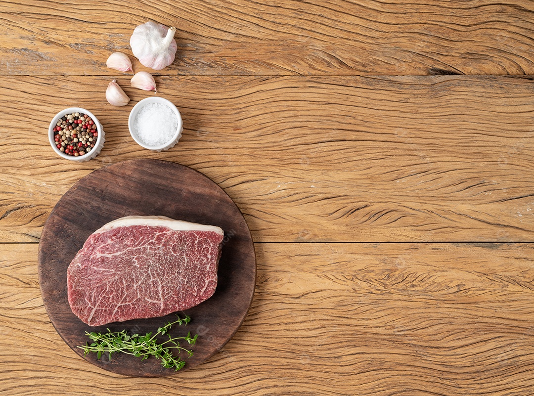 Carne assada de ombro wagyu crua sobre placa de madeira com temperos