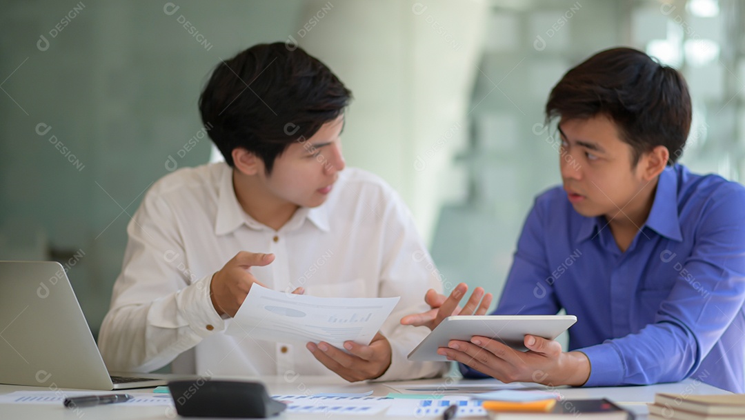 Equipe de profissionais com laptop e tablet consultam novos projetos para apresentação a executivos.