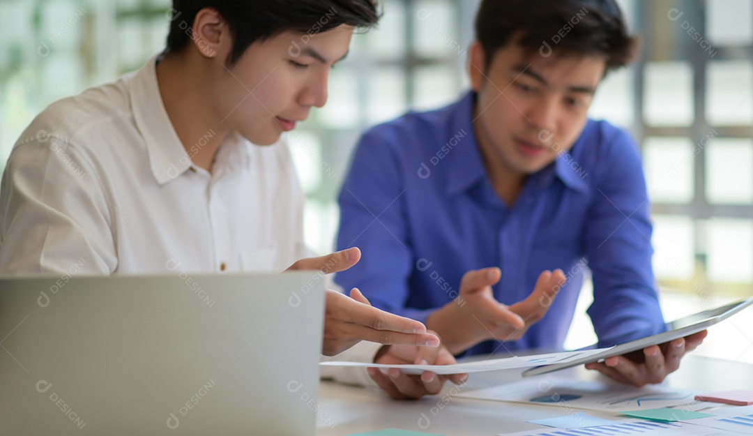 Equipe de profissionais com laptop e tablet consultam novos projetos para apresentação a executivos.