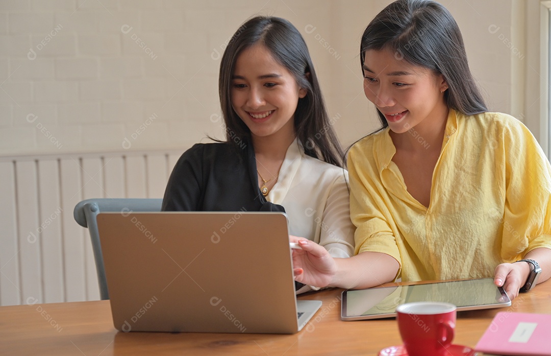 Duas estudantes universitárias usam um laptop para estudar on-line em casa para evitar o surto de vírus covid-19.