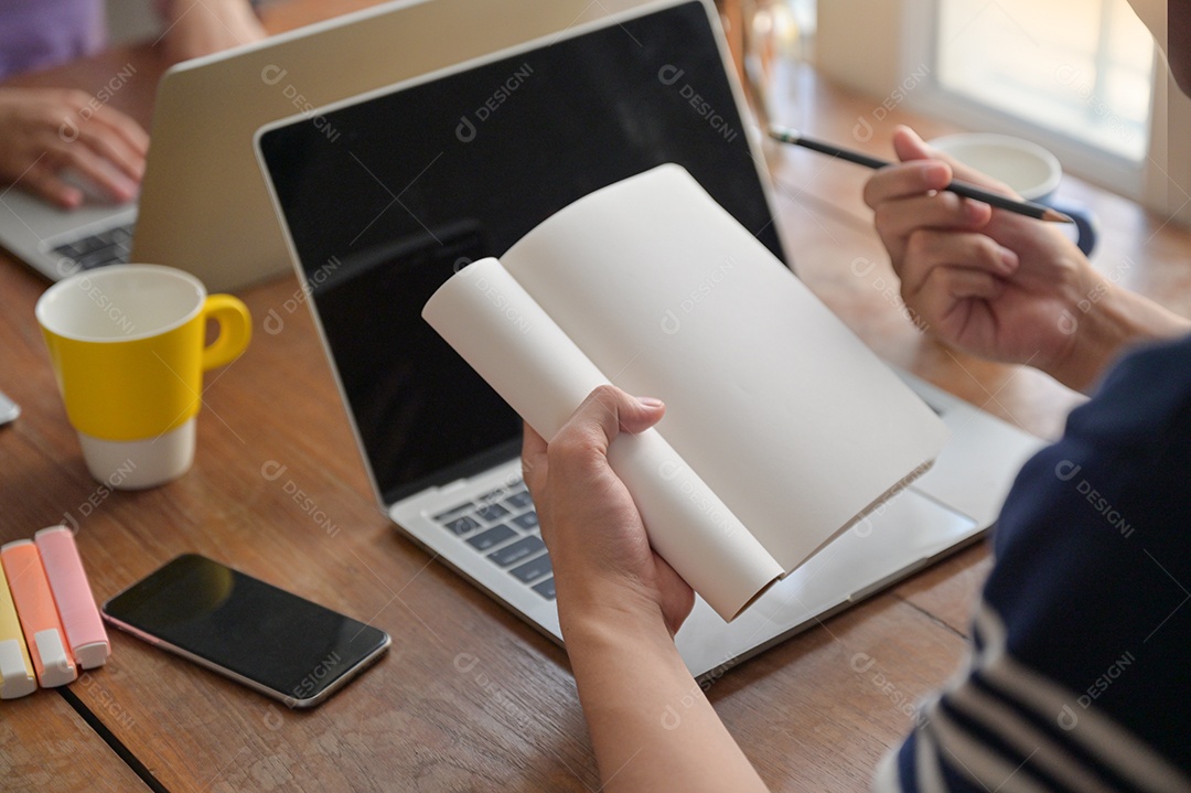 Alunos estão anotando no caderno. Eles estão estudando online com um laptop em casa.