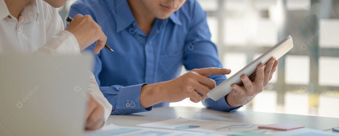 Homens jovens trabalhando juntos em tablet.