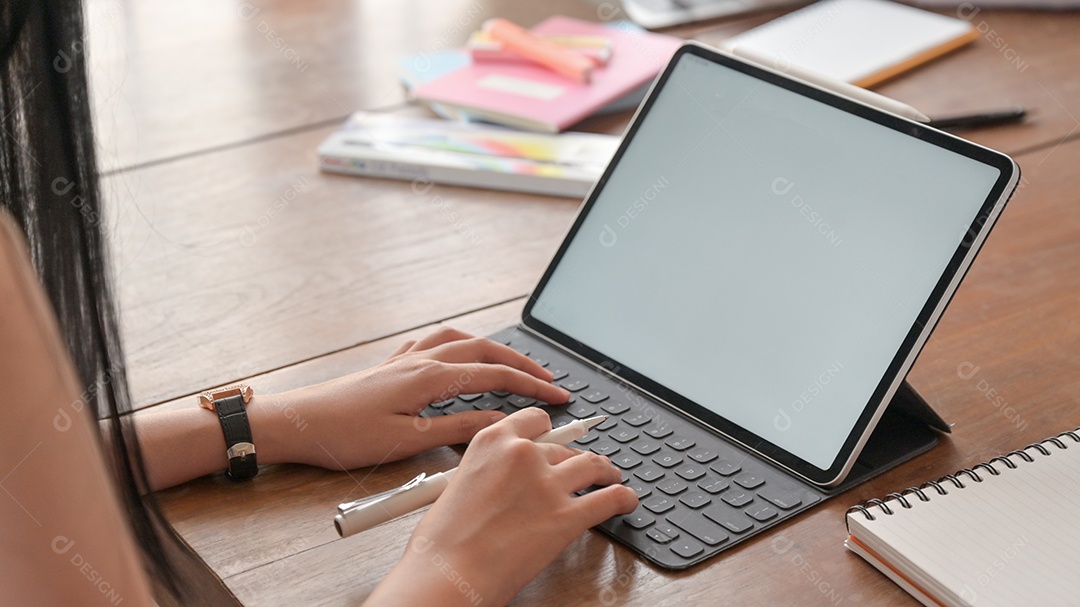 Tiro de mulher usando laptop e caneta na mão.
