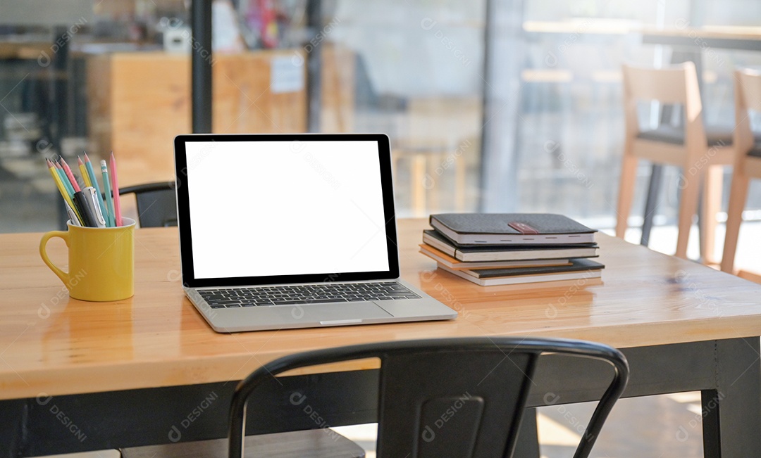 Laptop e um notebook com artigos de papelaria são colocados sobre a mesa no confortável espaço de trabalho.