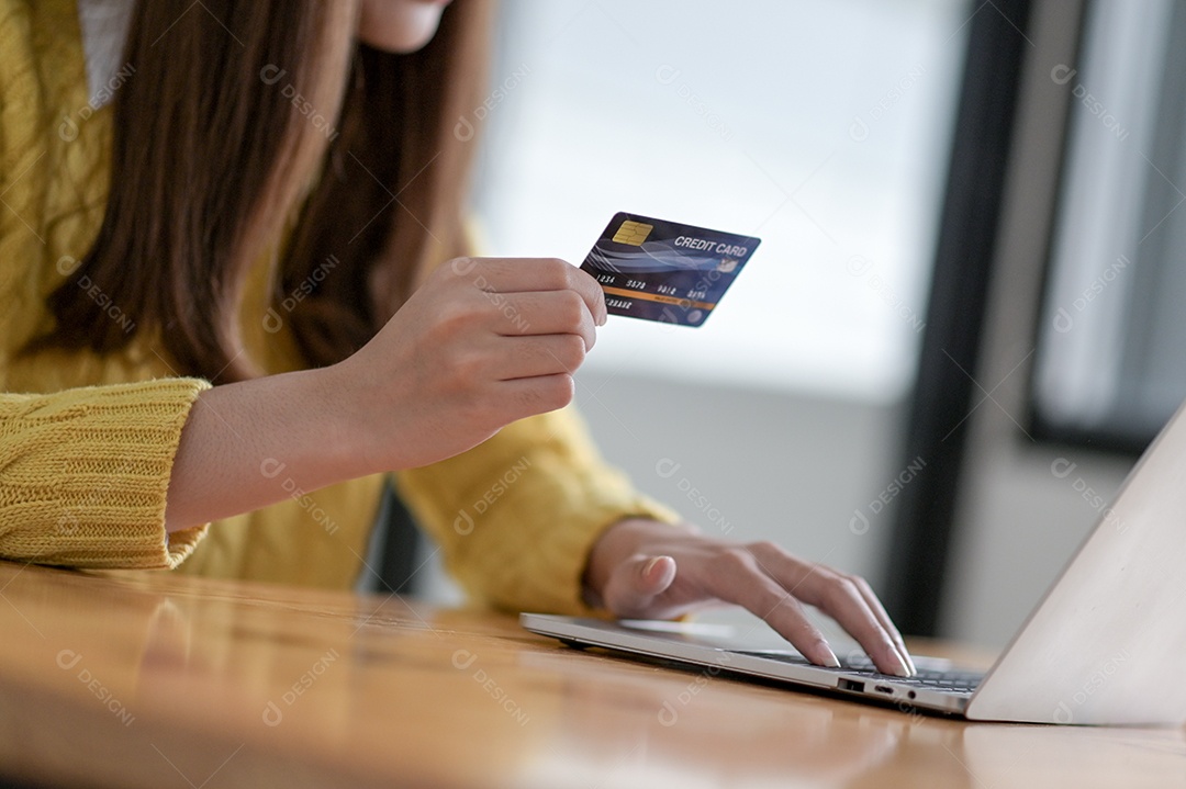 Mulher jovens estão usando um laptop para compras on-line e pagamentos com cartão de crédito.