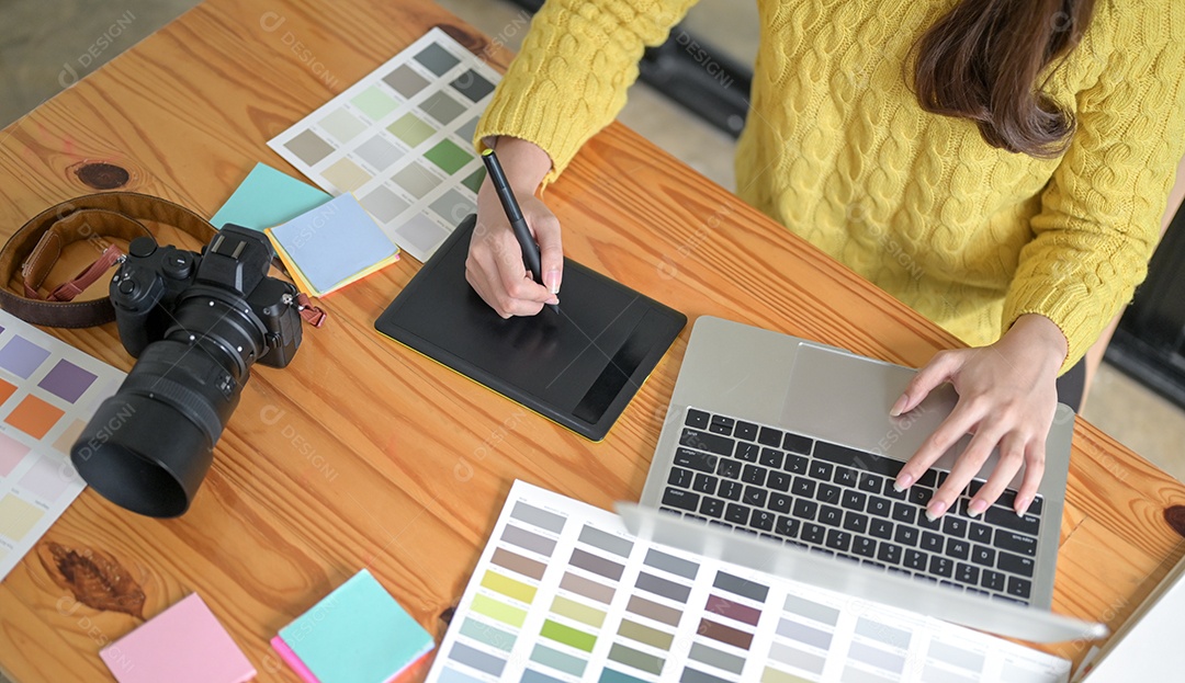 Designers estão trabalhando em um tablet e laptop de desenho.