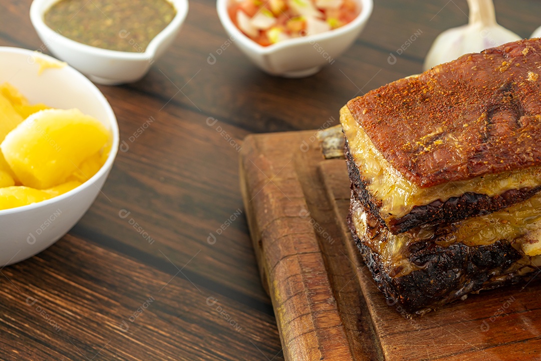 Costela bovina tradicional brasileira, com osso e acompanhamentos como: mandioca, chimichurri e salada de tomate e cebola