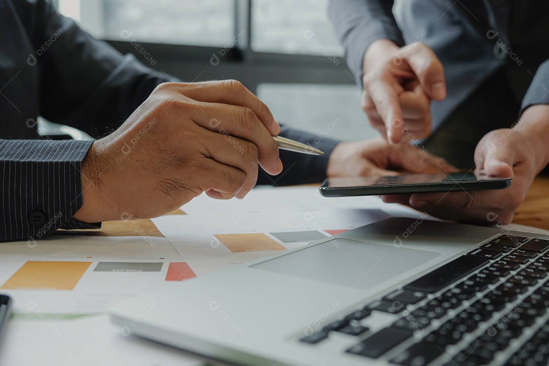 Dois empresários estão planejando o trabalho para atingir as metas organizacionais. Ele usa o tablet. Na mesa com um laptop.