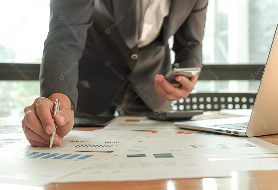 Empresários usando caneta, laptop e celular estão planejando um plano de marketing para melhorar a qualidade do trabalho da organização no futuro.