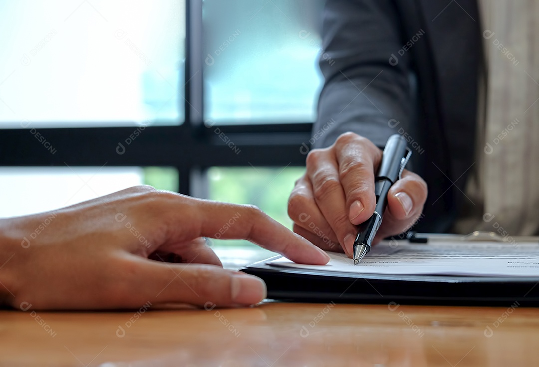 Mão do vendedor aponta o cliente para usar a caneta para assinar o contrato, Assinando o documento do contrato.