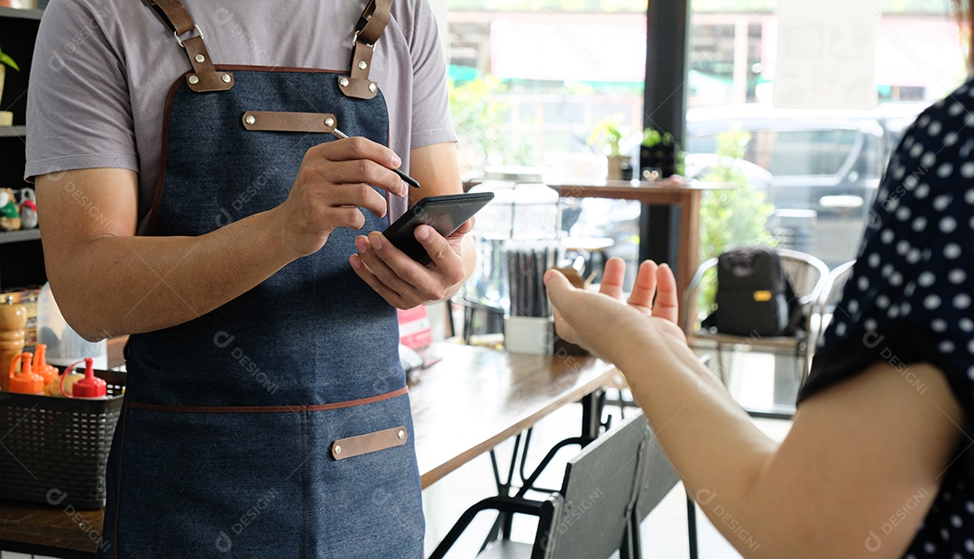 Funcionário segurando um smartphone para salvar o menu que o cliente pediu. O cliente está de pé para pedir o menu.