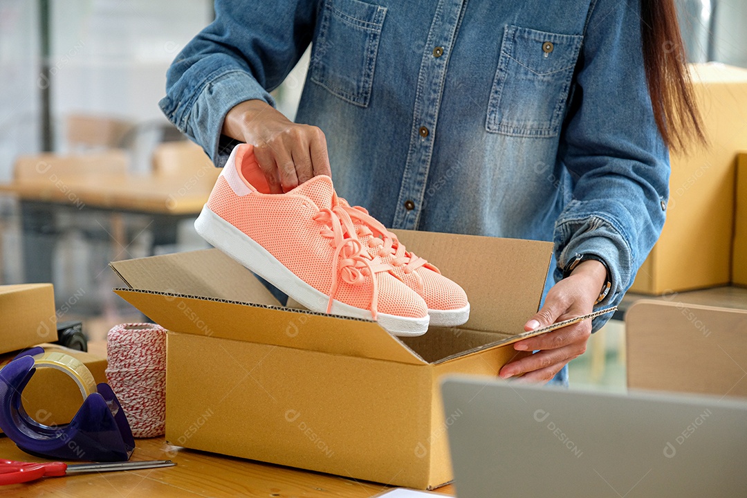 Vendedores online estão empacotando sapatos em caixas para entregar aos clientes.