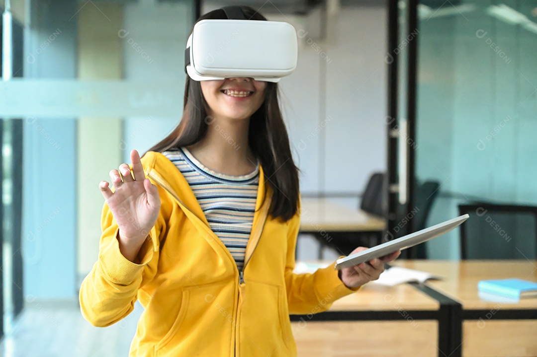 Menina asiática vestindo uma camisa amarela está usando o fone de ouvido VR. Ela está sorrindo.