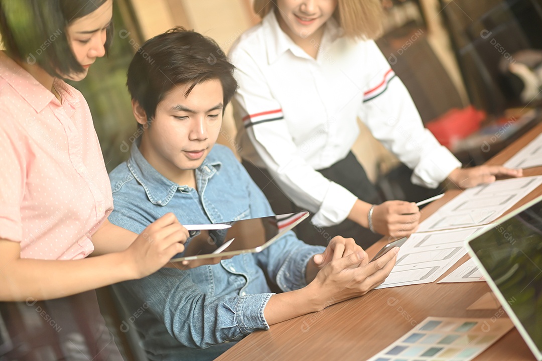 Equipe de designer gráfico está trabalhando no escritório. Eles usam laptop e tablet.