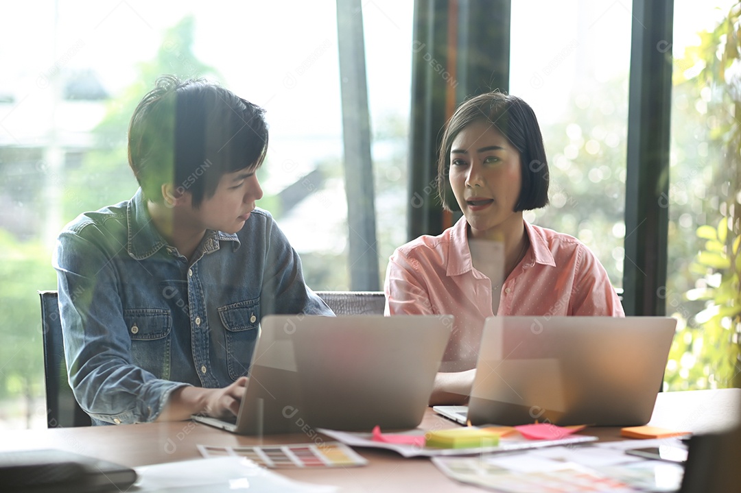 Nova geração de homem e mulher jovens estão sentados, consultando, trabalhando e usando laptop na mesa de escritório.