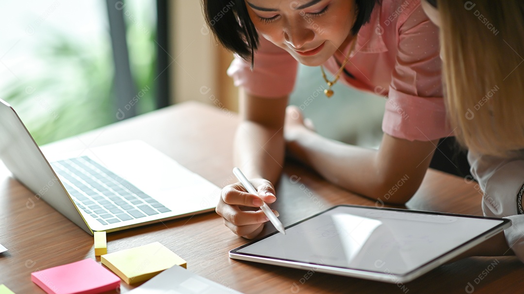 Designer gráfico feminino asiático trabalhando juntos no escritório Eles usam laptop e tablet.