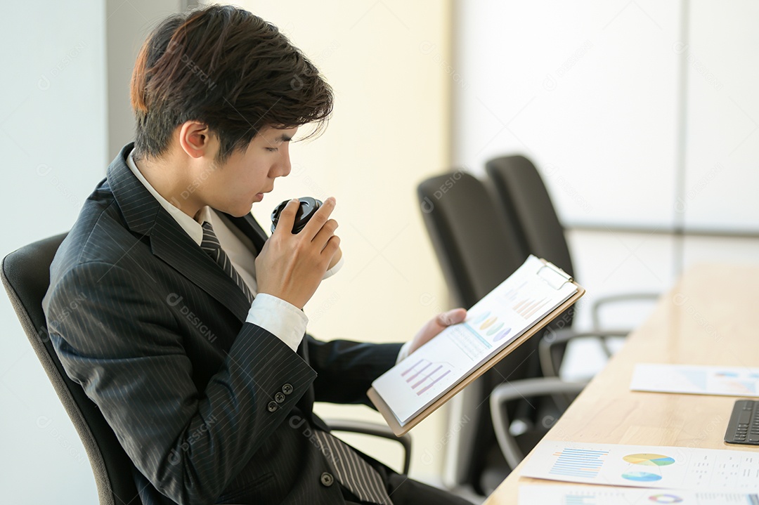 Jovem executivos estão verificando os ganhos da empresa. Ele toma café e verifica o gráfico.