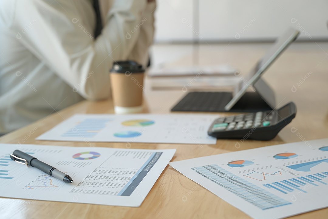 Caneta e gráficos para o desempenho da empresa na mesa. A parte de trás da gestão está descansando.