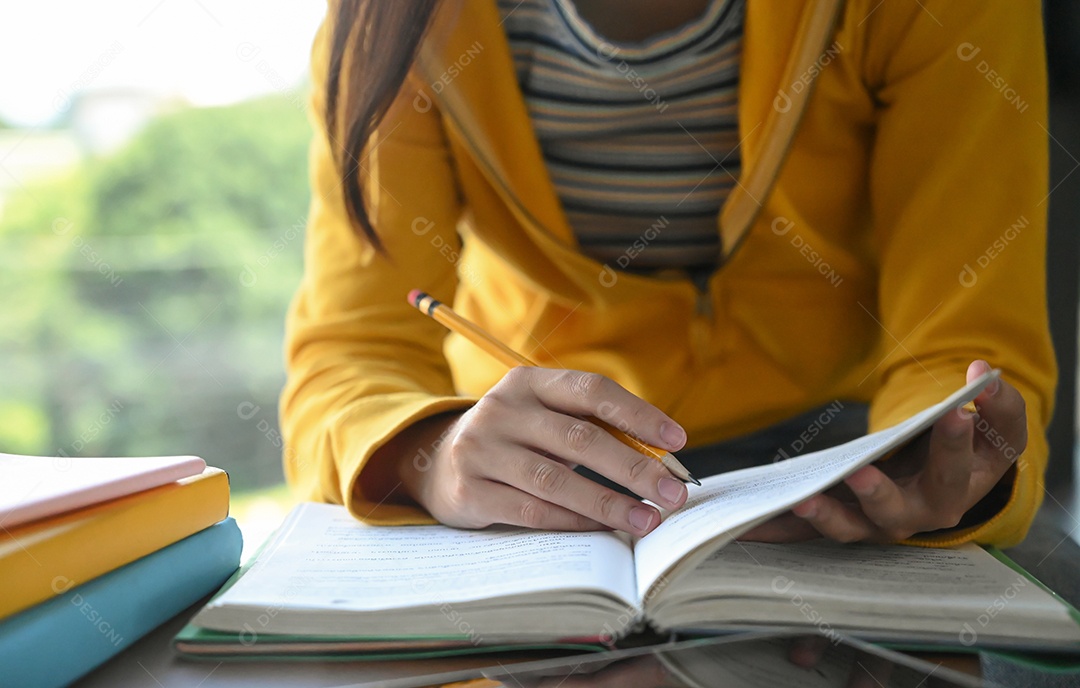 Alunos estão lendo livros e tomando notas para a preparação para o exame.