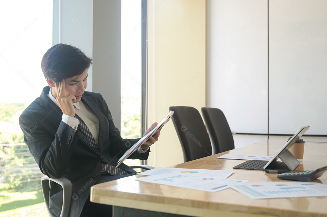 Jovem executivo estão verificando os ganhos da empresa. Ele usa o tablet e verifica os dados do gráfico.