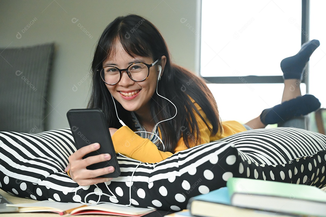 Mulher Estudantes do sexo feminino usam fones de ouvido dormem em travesseiros ouvem música de um smartphone