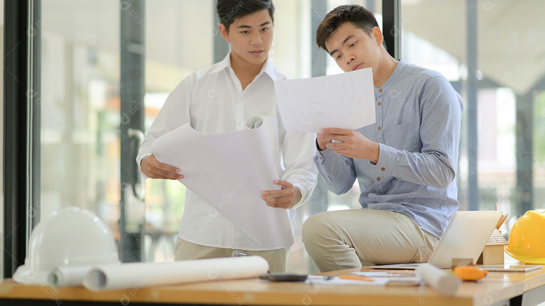 Arquitetos e engenheiros inspecionam planos e consultam para planejamento de projeto e construção.