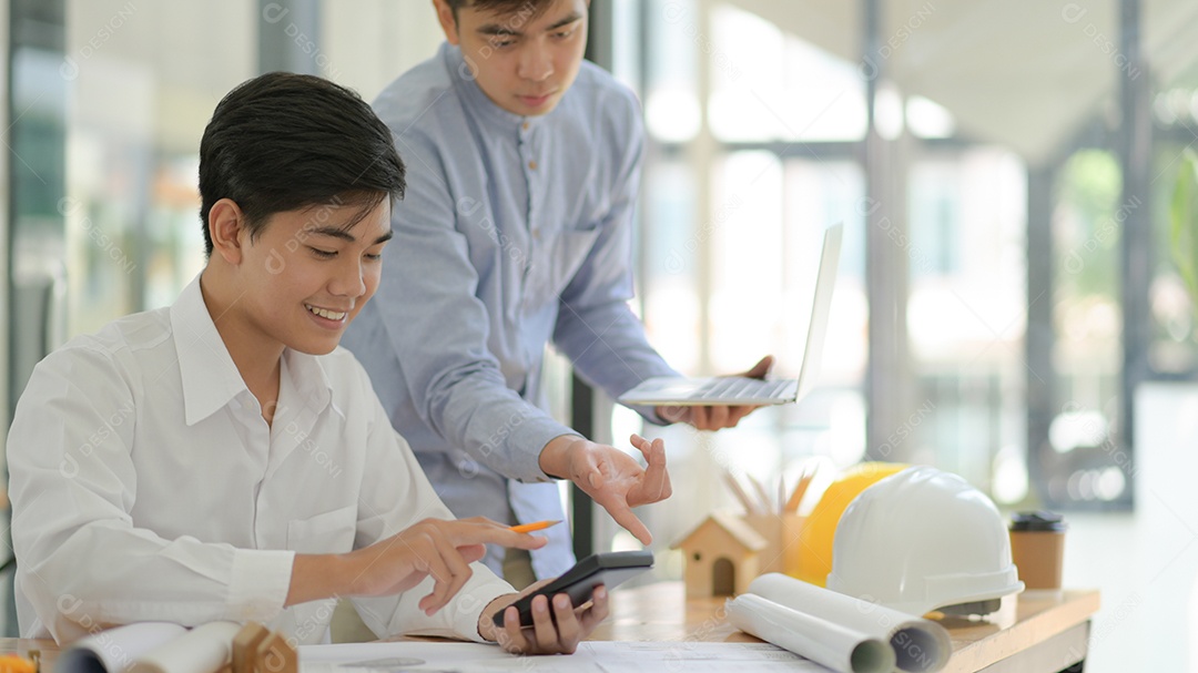 Arquitetos e engenheiros usam calculadoras e laptops para projetar e planejar a construção.