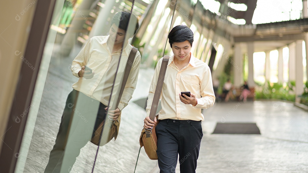 Nova geração jovem de negócios com uma bolsa de ombro olha para o smartphone na mão para verificar o trabalho.