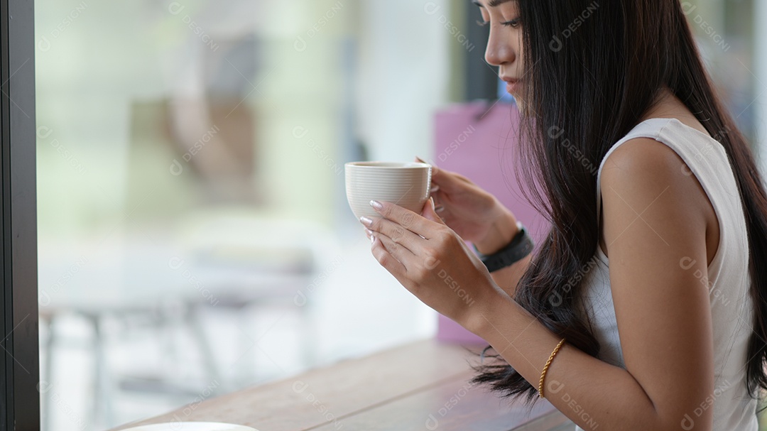 Menina asiática segurando uma xícara de café.