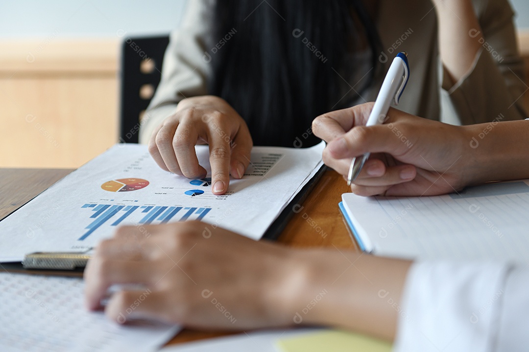 Equipe de funcionários do escritório feminino resume o orçamento para a apresentação executiva anual. Eles analisaram o gráfico de dados na mesa.