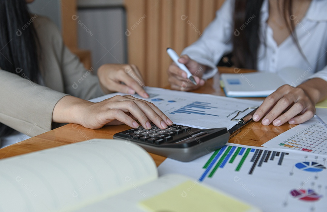 Equipe de funcionários do escritório feminino resume o orçamento para a apresentação executiva anual. Eles analisam o gráfico e usam a calculadora.