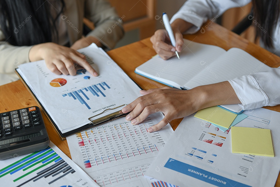 Equipe de funcionários do escritório feminino resume o orçamento para a apresentação executiva anual. Eles analisam o gráfico e usam a calculadora.