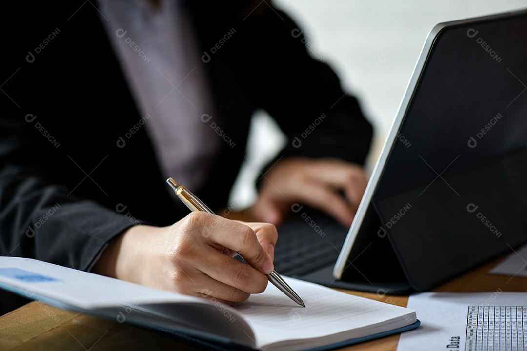 Equipe do escritório usa o laptop e nota no notebook na mesa no escritório.