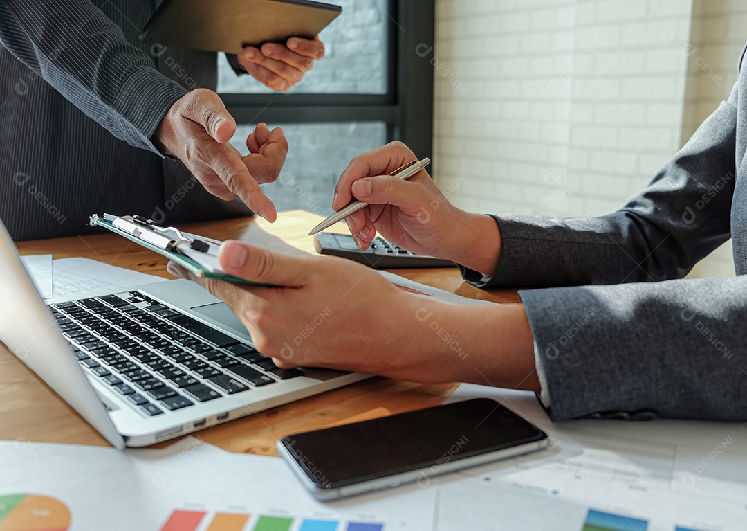 Equipe de gerenciamento trabalha no tablet para resumir o trabalho para atingir as metas organizacionais. Apontando e caneta executiva no tablet com laptop, documento, celular colocado na mesa.