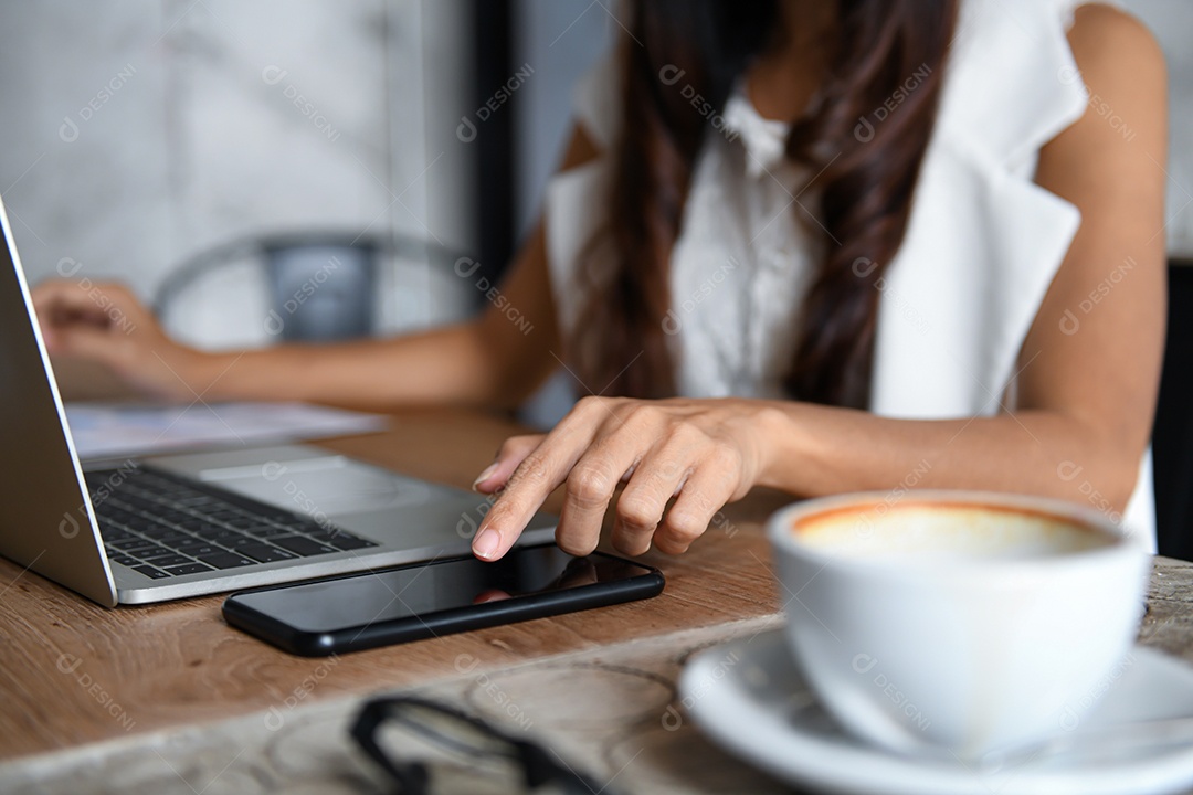 Empresários femininos estão usando smartphone e laptop para trabalhar no escritório.