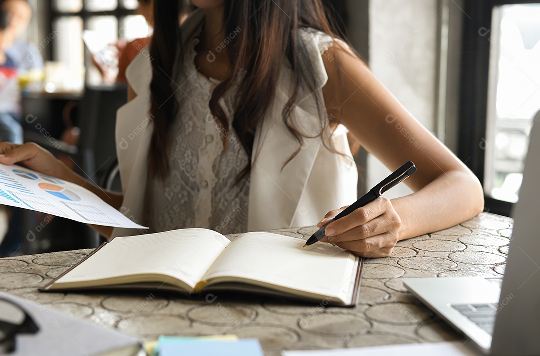 Conceito de negócios, mulher executivas estão verificando dados de gráficos e tomando notas. Ela segura uma caneta e um gráfico.
