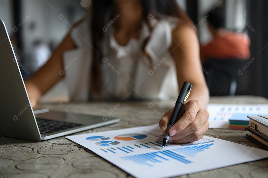 Empresário feminino estão verificando gráficos de dados e usando laptop.