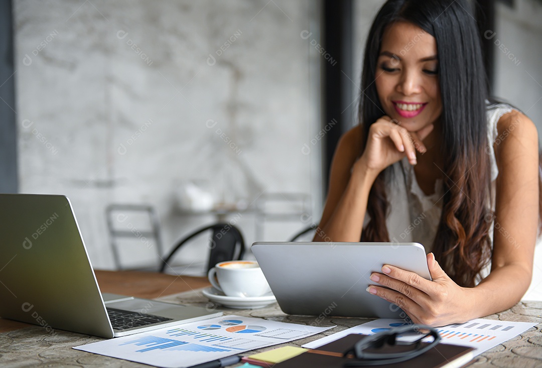 Empresário Femininos estão usando o tablet durante o lazer. Ela sorri feliz. Gráficos, documentos colocados sobre a mesa.