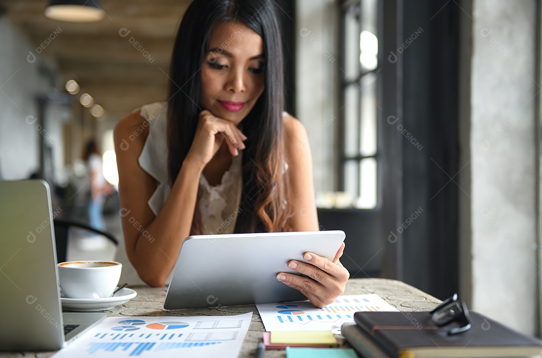 Empresário Femininos estão usando o tablet durante o lazer. Ela sorri feliz. Gráficos, documentos colocados sobre a mesa.