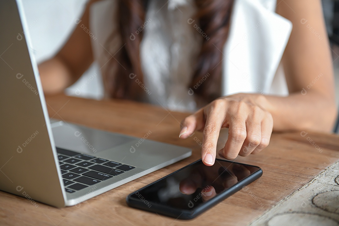 Mão de uma mulher de negócios está usando um telefone celular para encontrar informações. Ela está digitando uma mensagem na tela do telefone.
