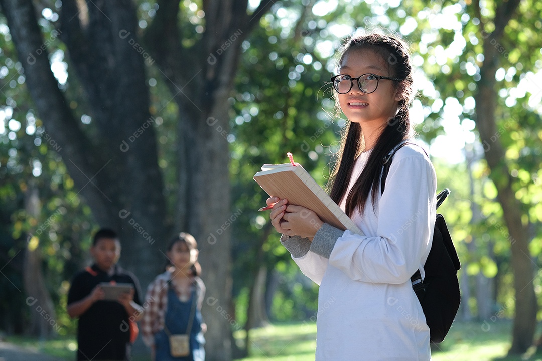 Estudante asiática lendo um livro no jardim.