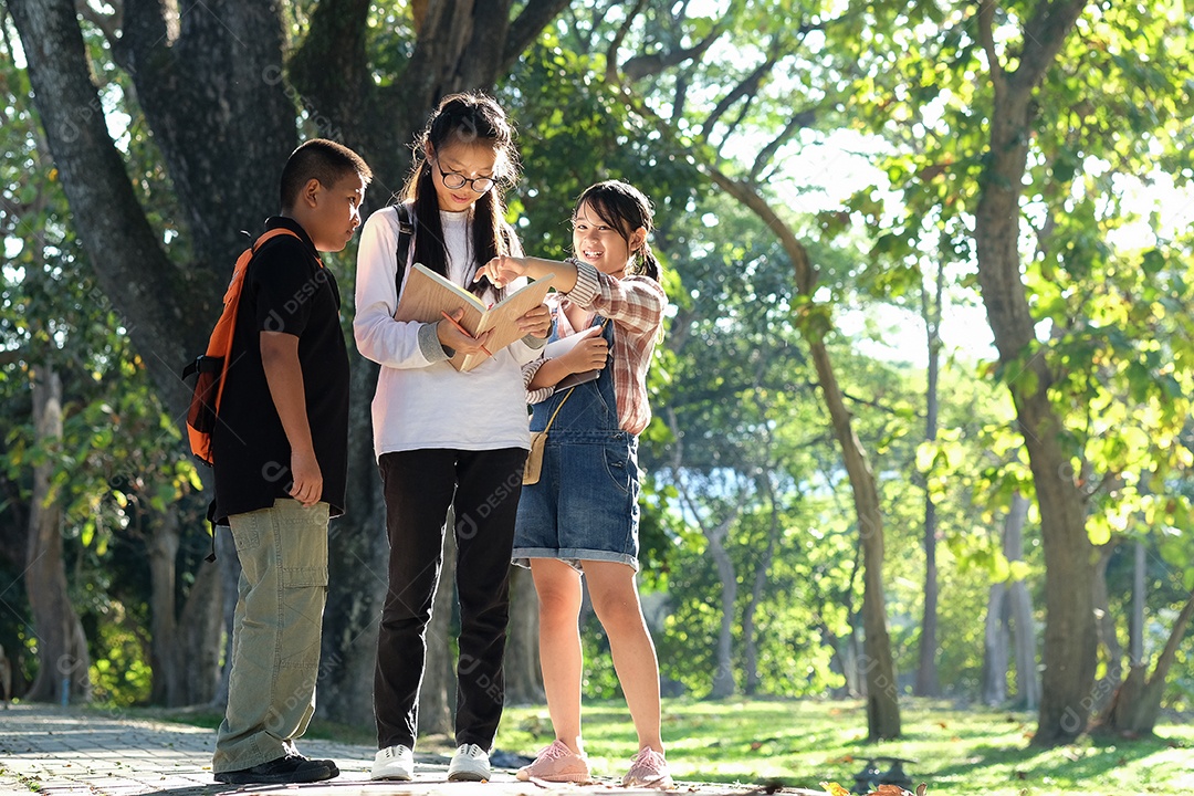 Menino asiático e menina três pessoas estão lendo no jardim.